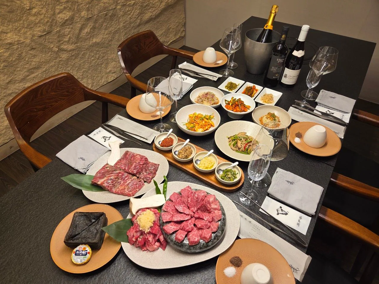 ワインとおかず、牛肉が並ぶ黒牛亭の個室の食卓